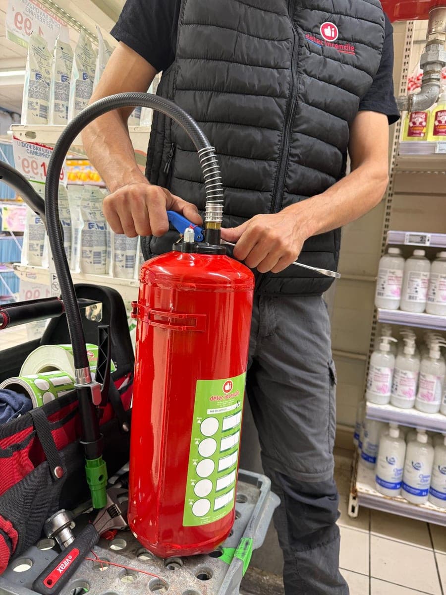 Technicien Détec Incendie rechargeant un extincteur lors d’une intervention sur site